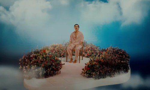 Still from the video, Sávio seated on a flower island